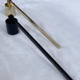 Side by side black and gold wick snuffers on a white background