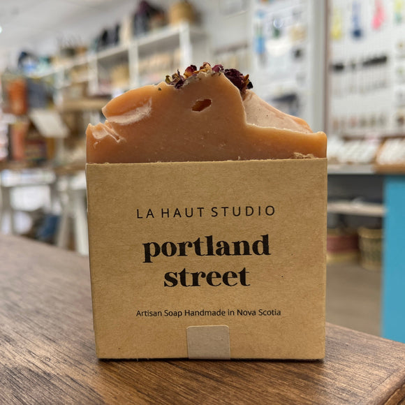 Light brown bar soap in kraft paper label. Soap bar has floral details at the top