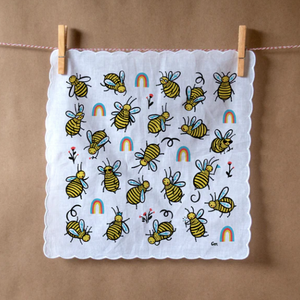 Round buzzy bees surrounded by rainbows are printed on this white hankie with scalloped edges