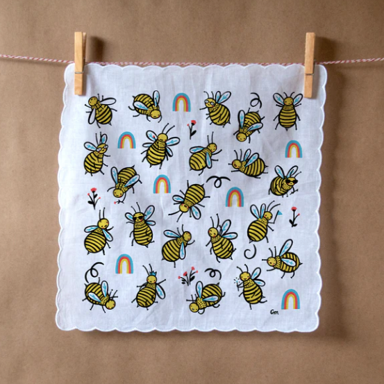 Round buzzy bees surrounded by rainbows are printed on this white hankie with scalloped edges